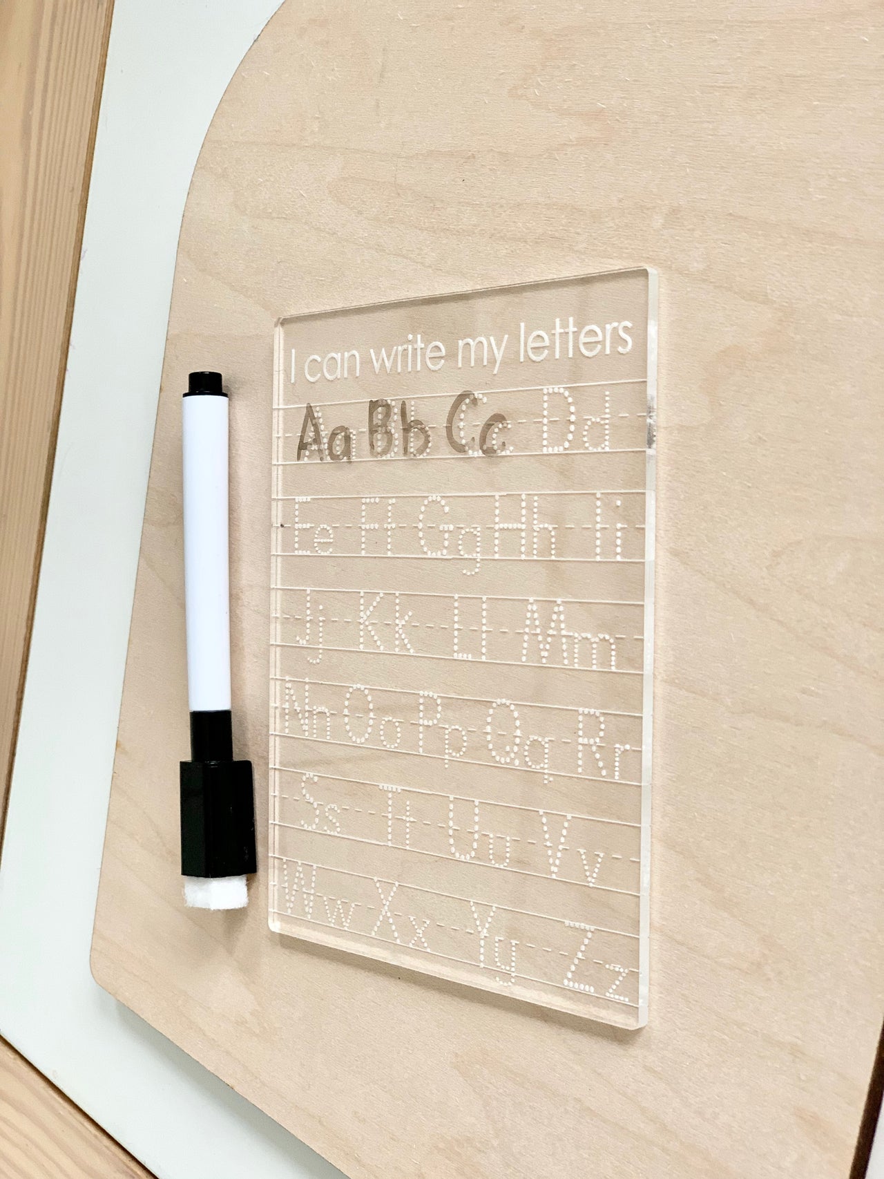 Mini acrylic dry erase tracing board with uppercase and lowercase letters and dry erase marker on wood background