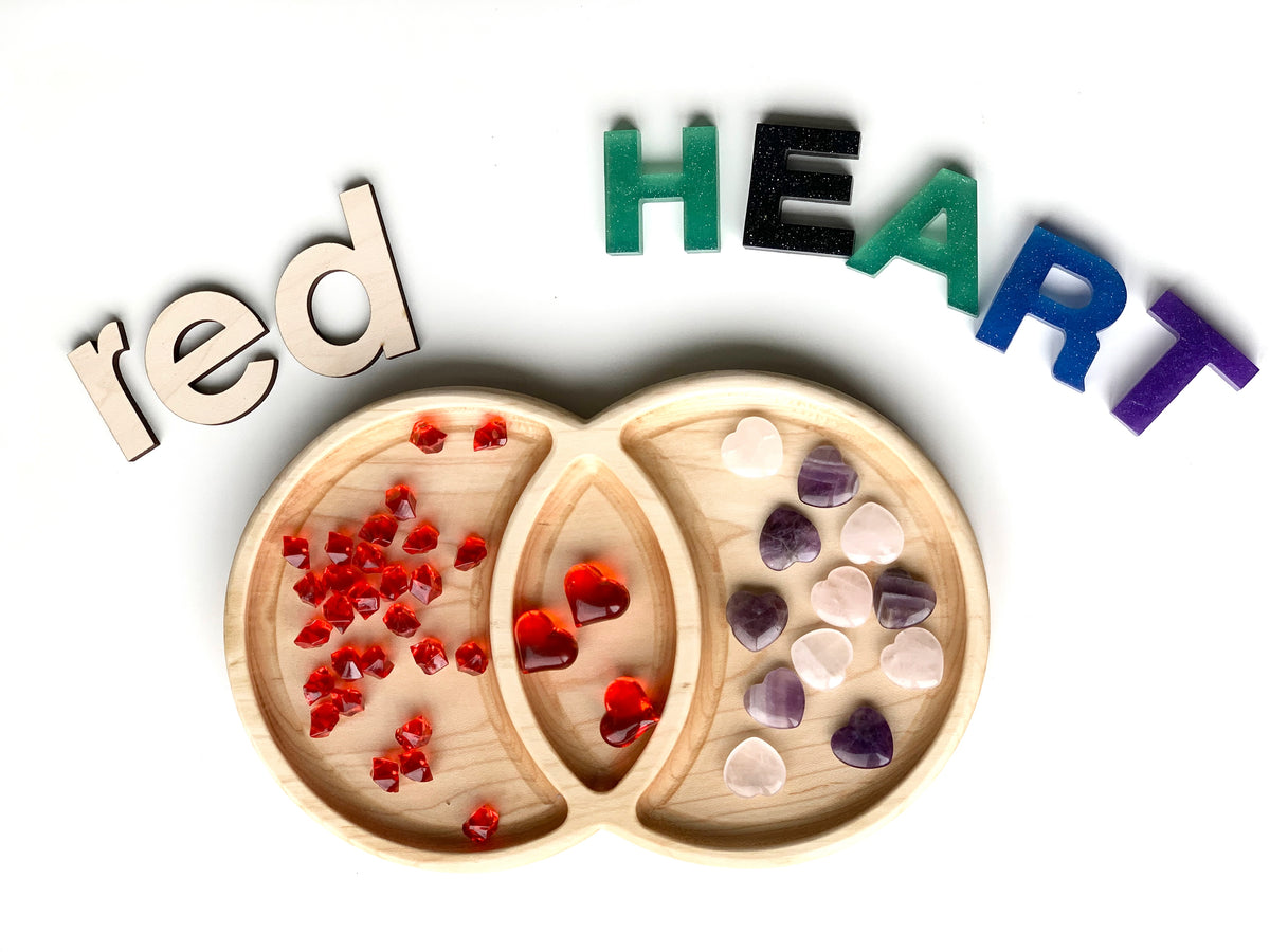 Wooden Venn diagram tinker tray with red and purple heart-shaped counters and colorful letters spelling red HEART