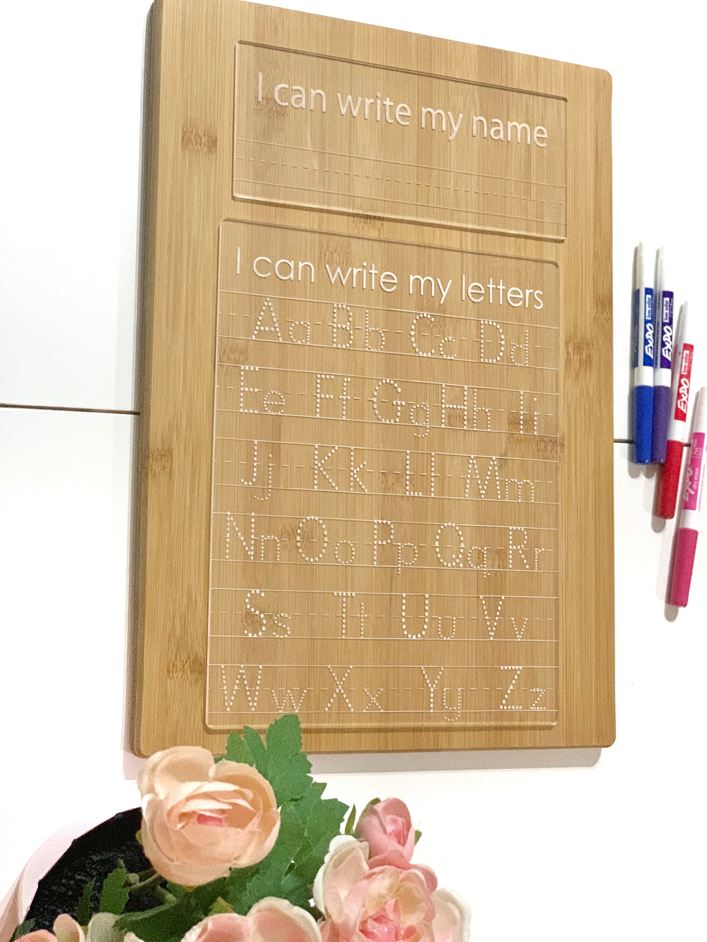 Wooden acrylic dry erase tracing board engraved with uppercase and lowercase letters and name writing section with markers nearby