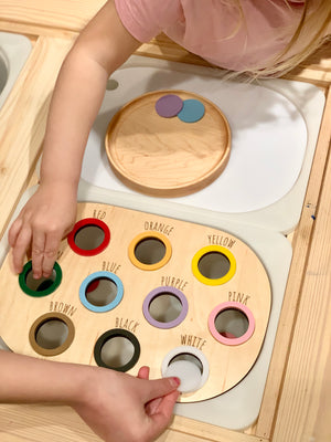 Child playing with natural wooden colour sorting Flisat table bin lid with painted color labels on light wood table