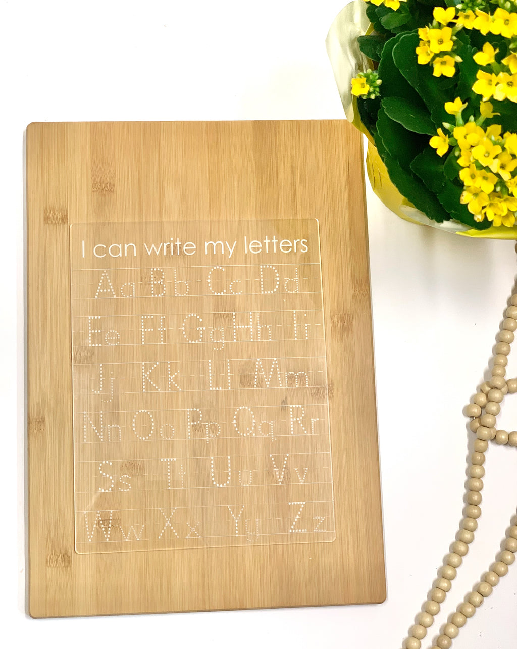 Clear acrylic dry erase tracing board with uppercase and lowercase alphabet letters engraved on wood background