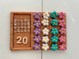 Wooden 20 frame sensory tray with clear acrylic gems and colorful felt flowers arranged in rows on natural wood background