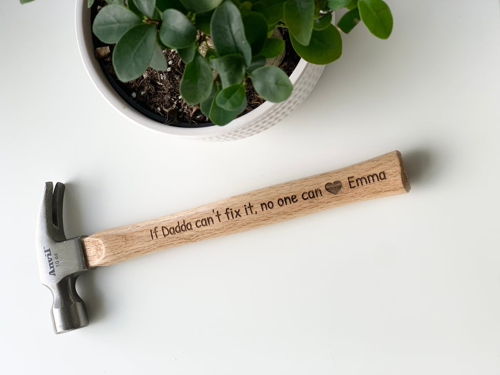 Personalized wooden hammer with laser engraved custom message and heart symbol on natural wood handle near green plant