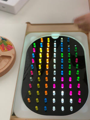 Small hole peg board insert with colorful translucent pegs arranged in rows on geometric light board tabletop accessory
