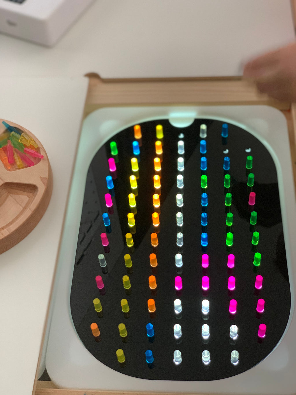 Small hole peg board insert with colorful translucent pegs arranged in rows on geometric light board tabletop accessory