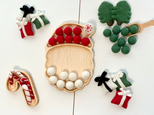 Wooden Candy Cane Plate Sensory Tray with red and white felt balls and small felt gift decorations on white surface