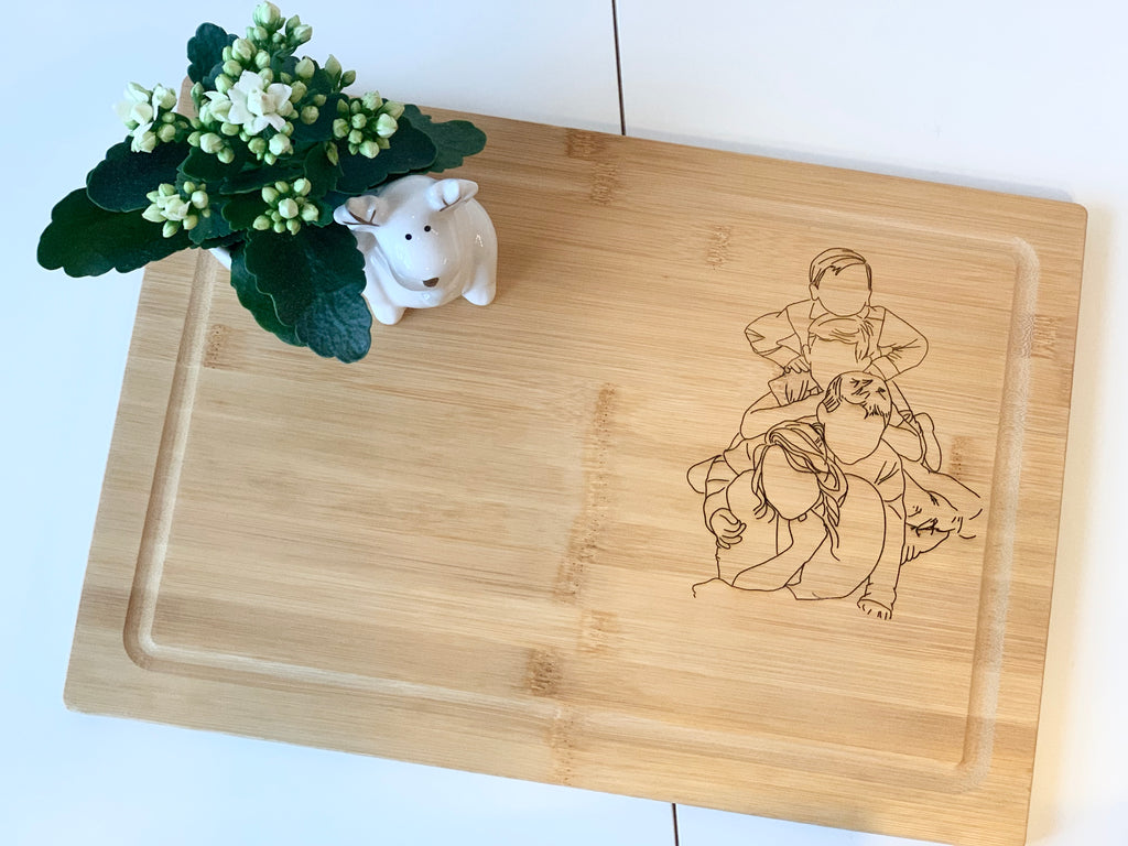 Personalized bamboo cutting board with engraved cowboy and dog design and small white flower pot on white table