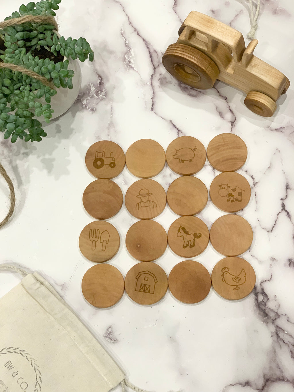 Wooden farm memory game pieces with engraved tractor, pig, farmer, cow, horse, barn, chicken, and utensils on marble surface
