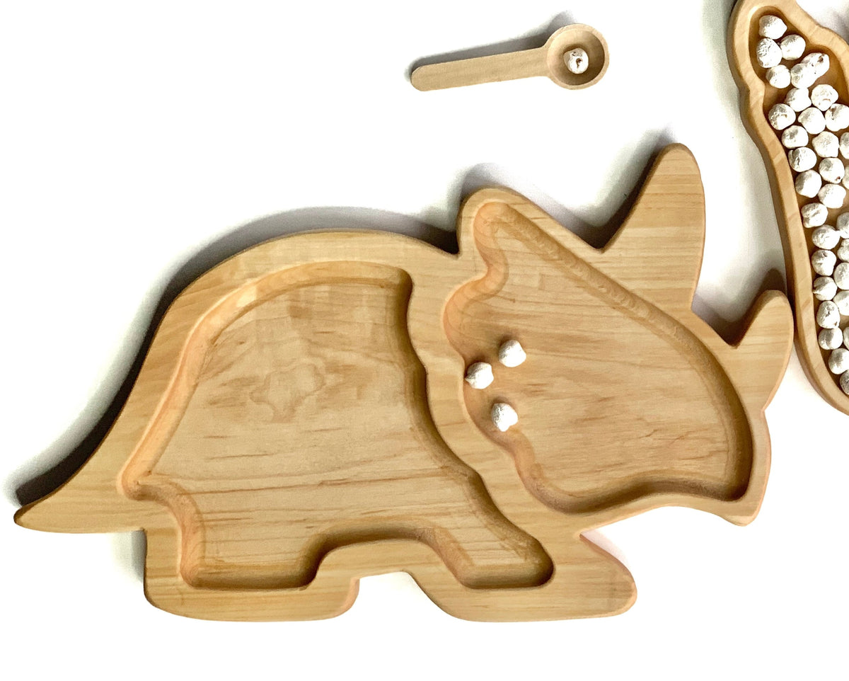 Natural wooden Triceratops shaped plate with carved sections for sensory play on white background