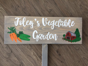 Large personalized wooden garden sign with white cursive letters, painted carrots, cucumbers, and red barn illustration on wood grain background