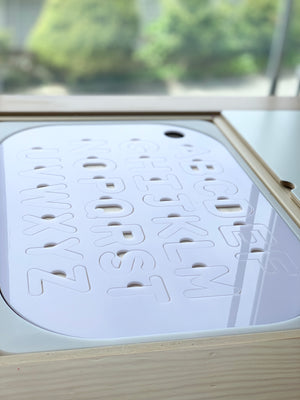 Maple plywood Flisat table insert with white acrylic uppercase alphabet puzzle letters cut out on wooden bin background