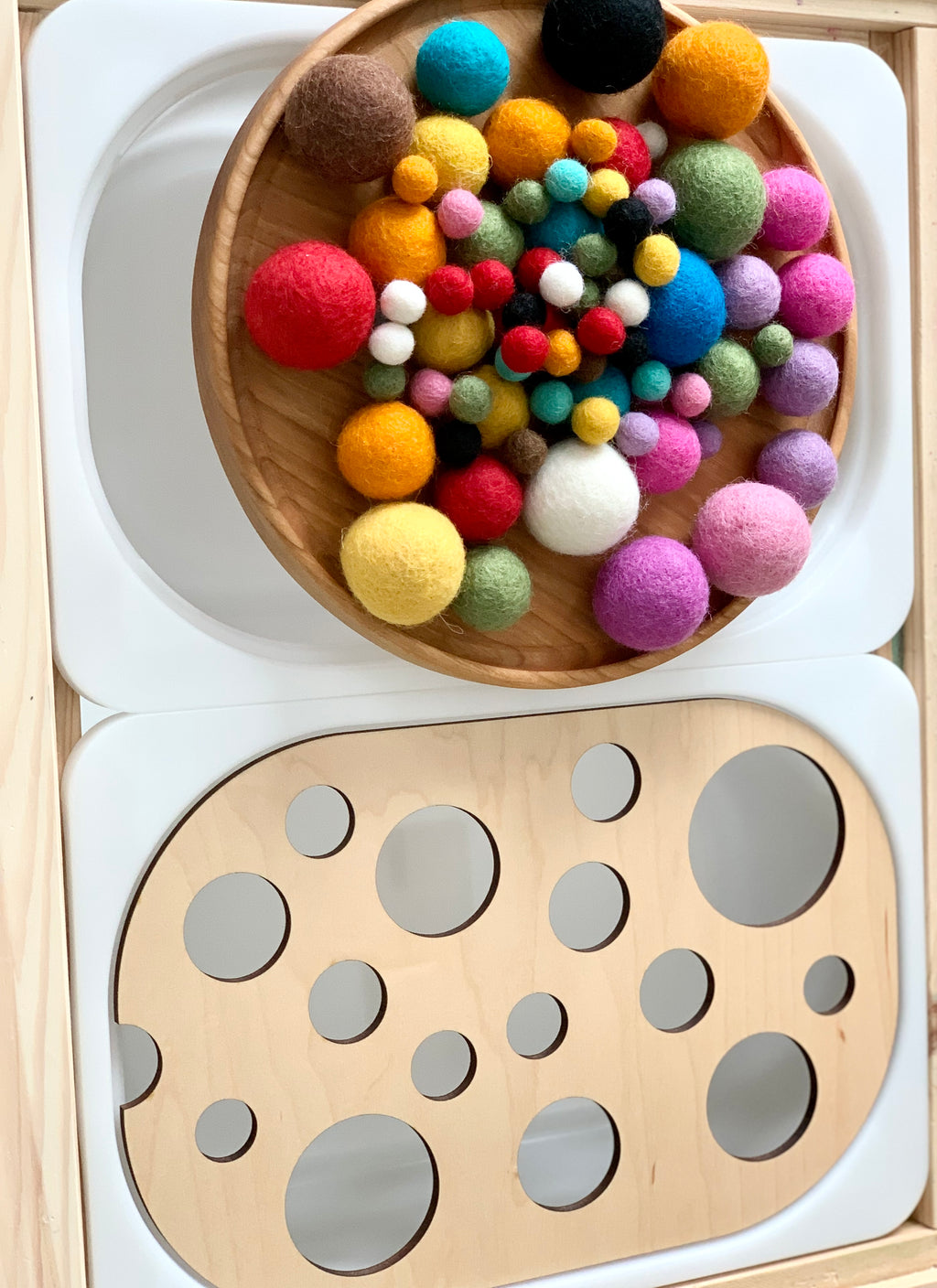 Wooden Circle Ball Sorter Flisat tabletop insert with various colorful felt balls on a wooden tray on white surface