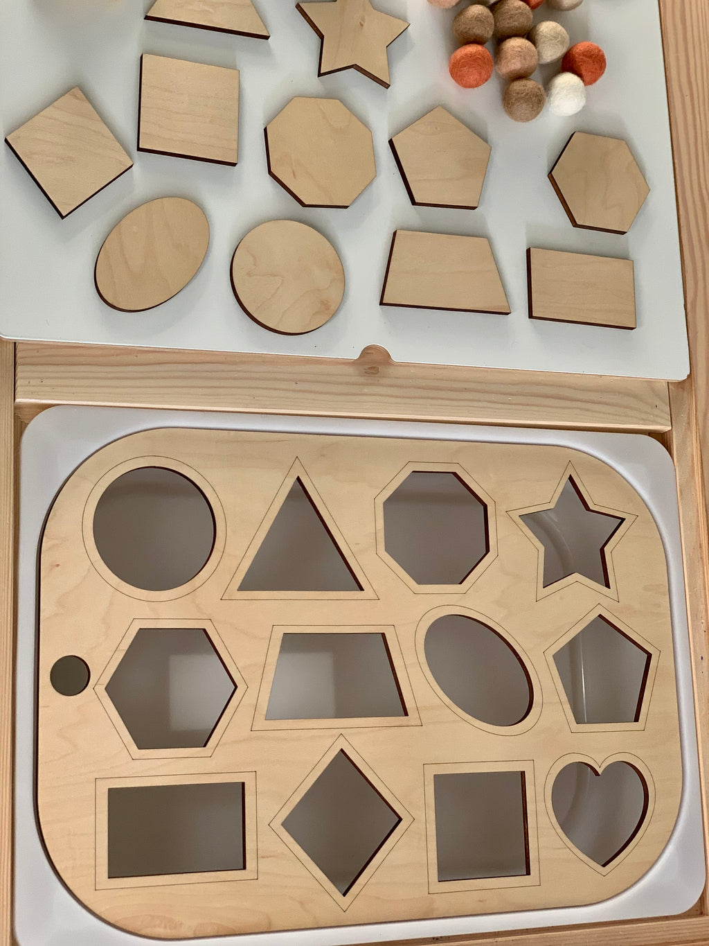 Maple plywood shape sorter insert with geometric wooden shapes and felt balls on white Flisat table surface