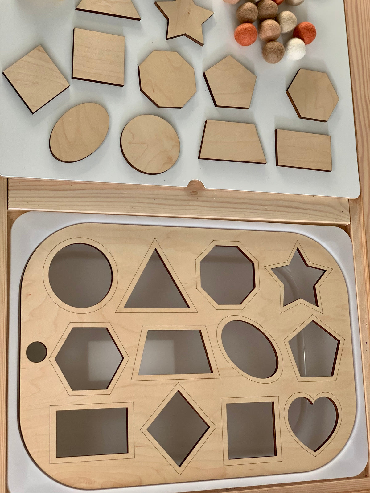 Maple plywood shape sorter insert with geometric wooden shapes and felt balls on white Flisat table surface