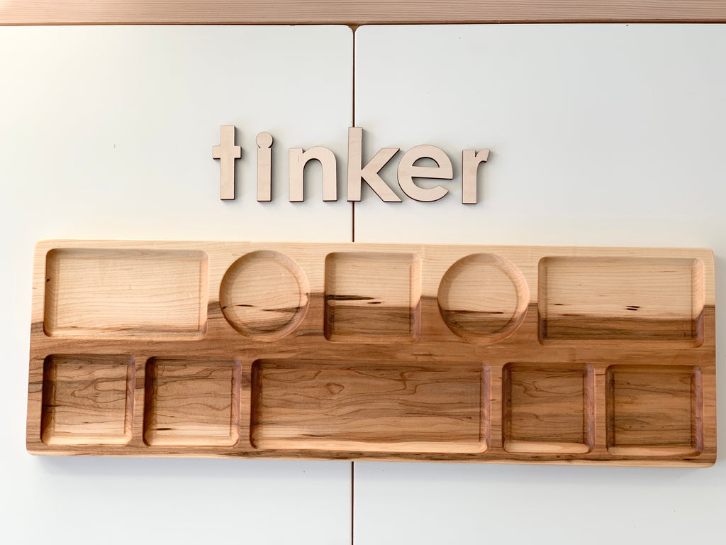 Extra large wooden tinker tray plate with multiple shaped compartments on white surface and wooden letters spelling tinker above