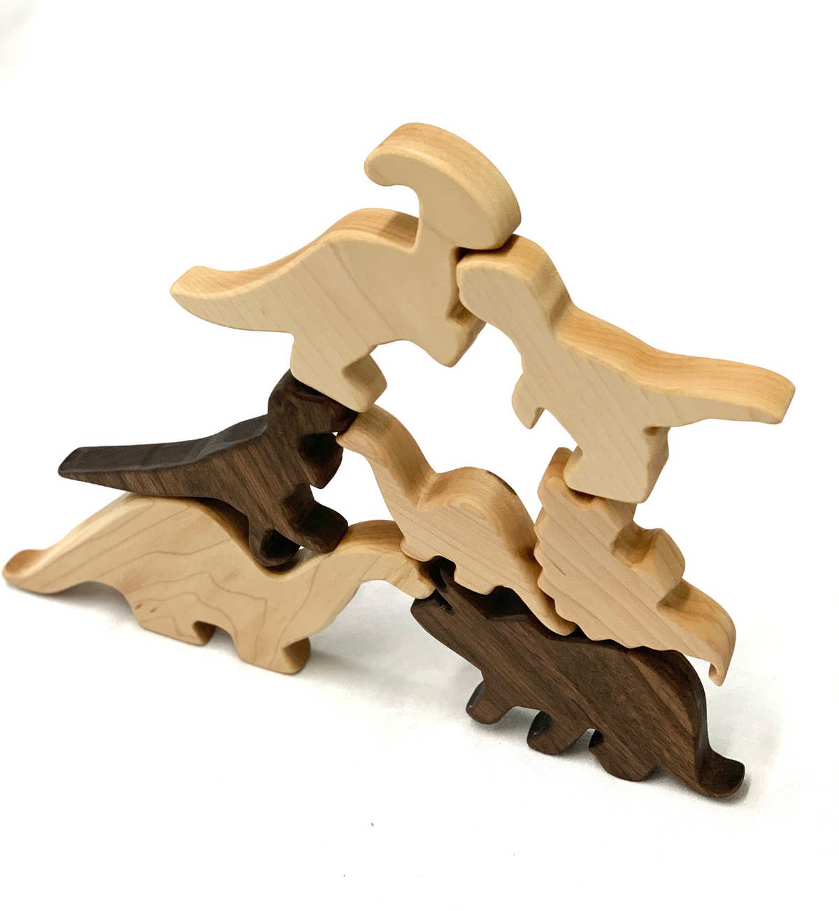 Set of six natural and dark wooden dinosaur toy figurines stacked on white background
