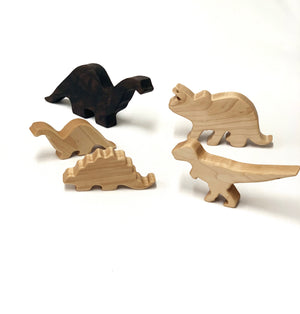 Set of five natural and dark wooden dinosaur toy figurines on white background for imaginative play