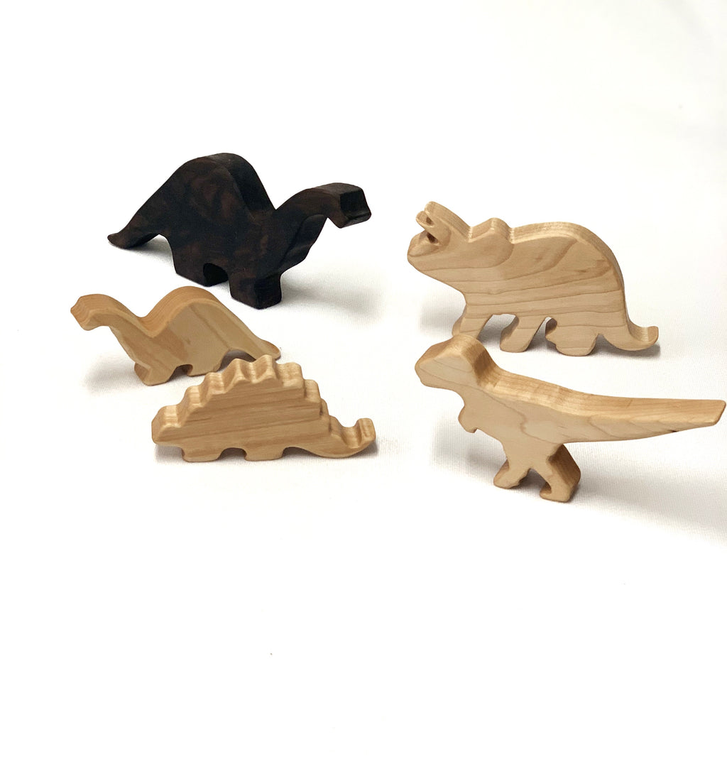 Set of five natural and dark wooden dinosaur toy figurines on white background for imaginative play