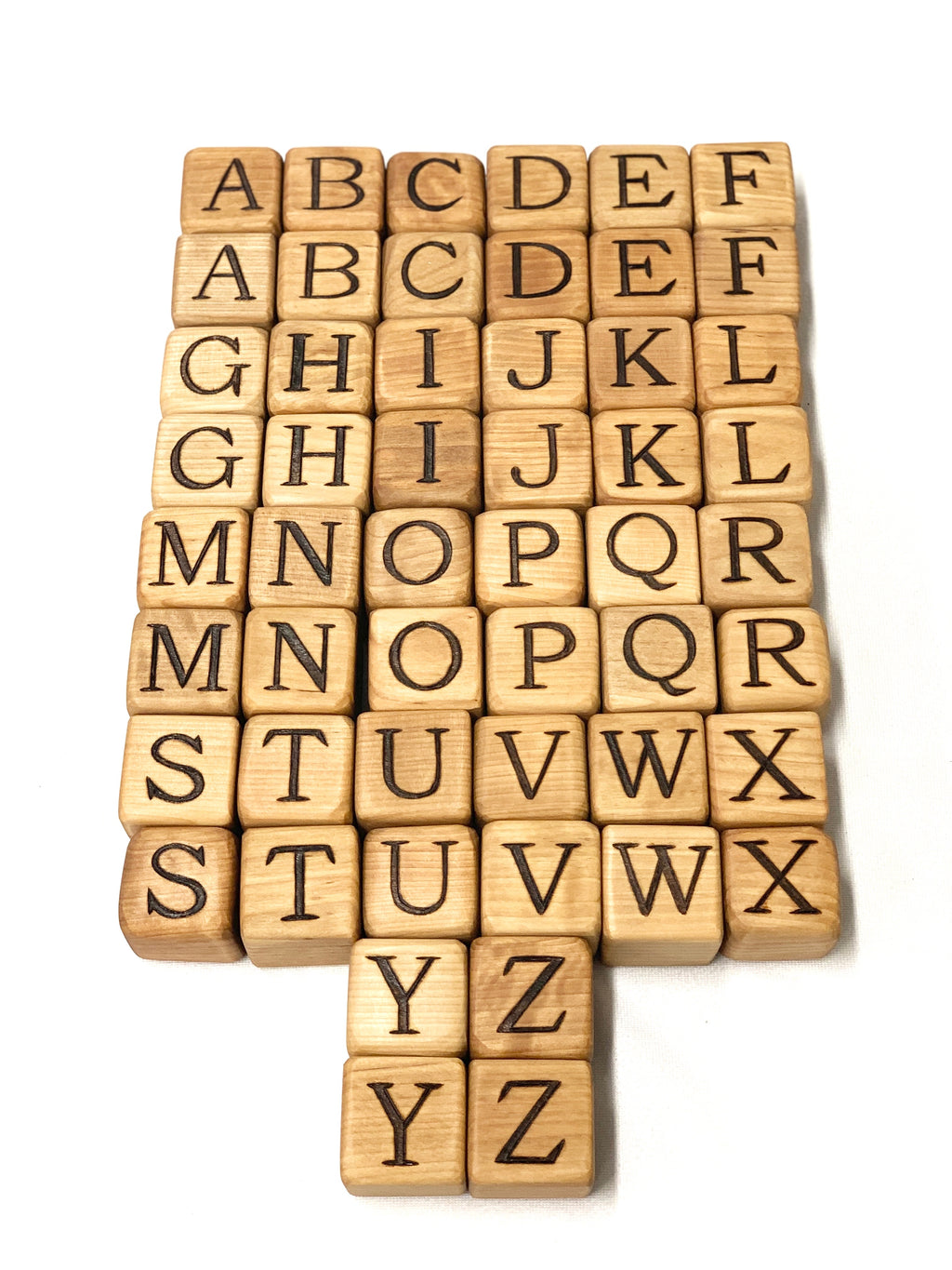 Natural wooden 2-inch alphabet blocks with engraved capital letters arranged in rows on white background