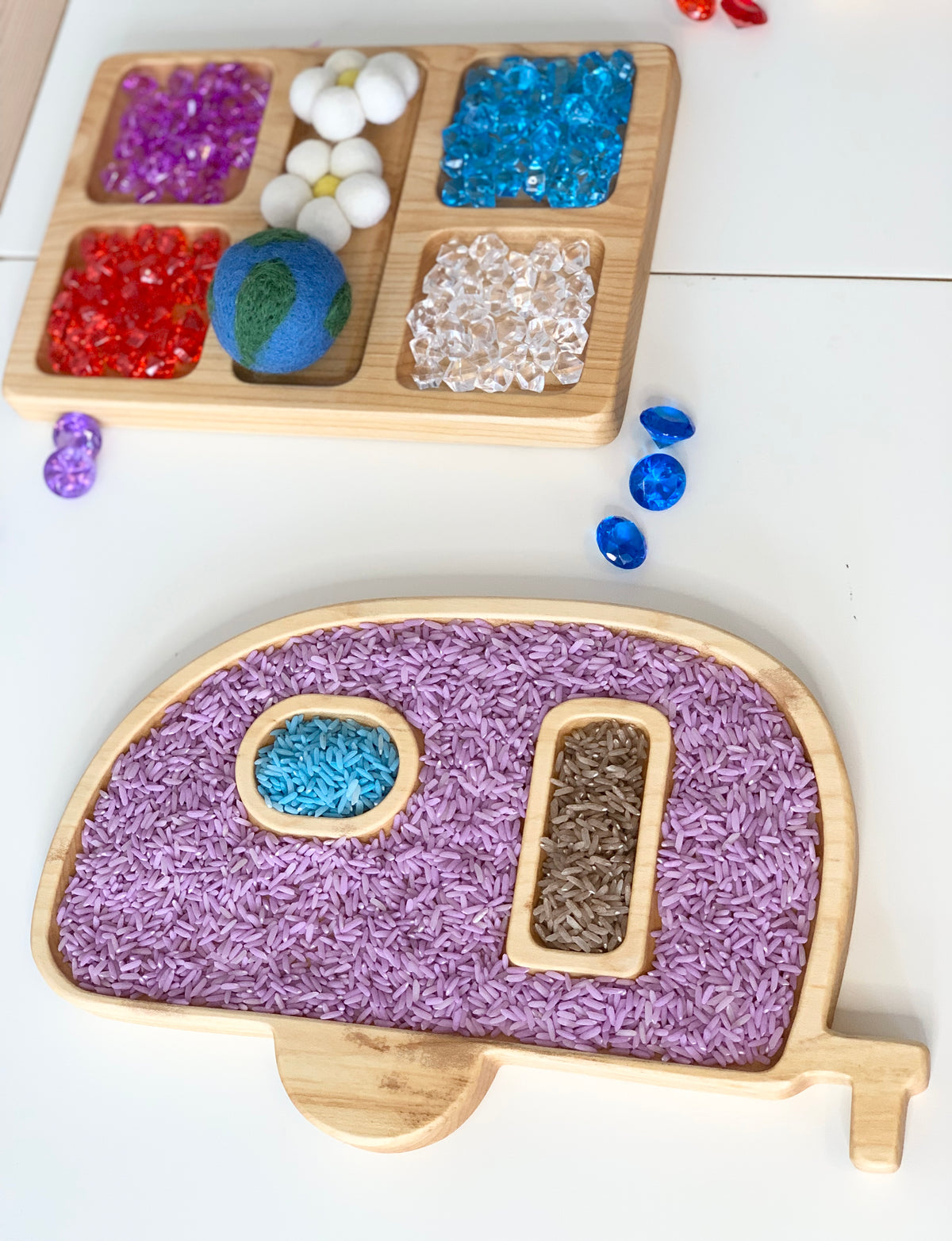 Wooden camper-shaped sensory tray filled with colored rice and small wooden compartment tray with colorful sensory gems and felt balls