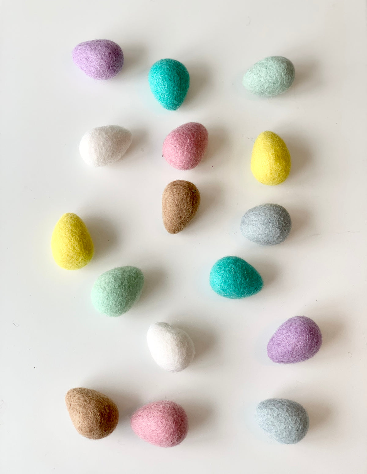 Assorted colorful felt Easter eggs made from pure wool arranged on white background