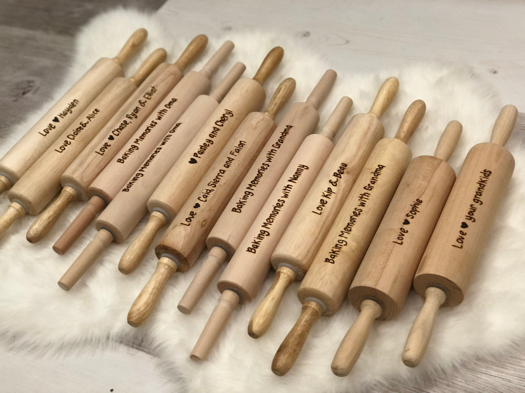 Row of personalized wooden rolling pins with custom engraved baking and love messages on light wood grain surface
