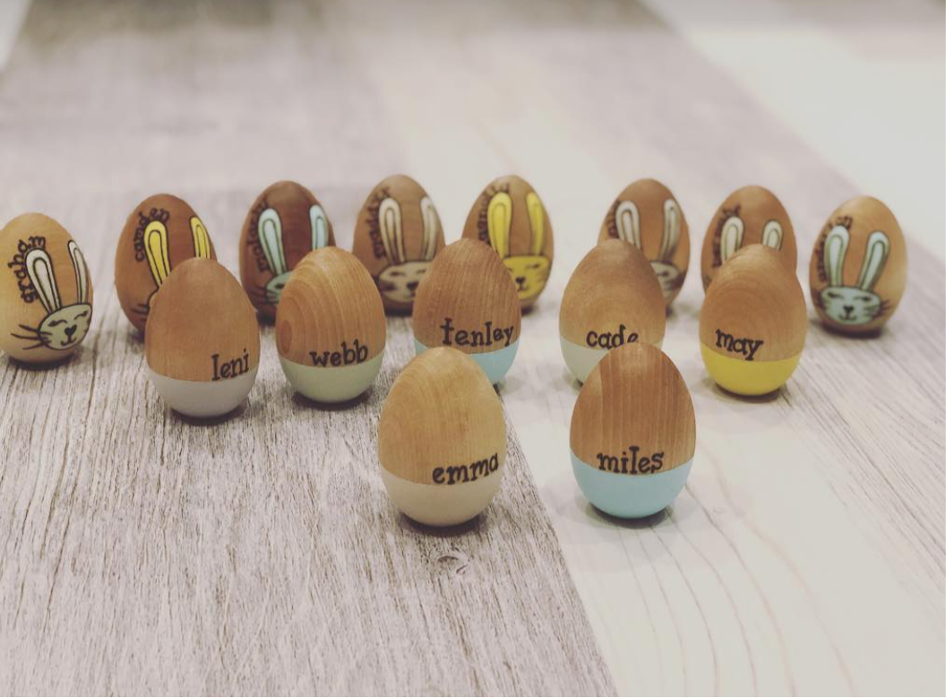 Personalized wooden Easter eggs with pastel bases and hand-painted bunny faces displayed on wood surface