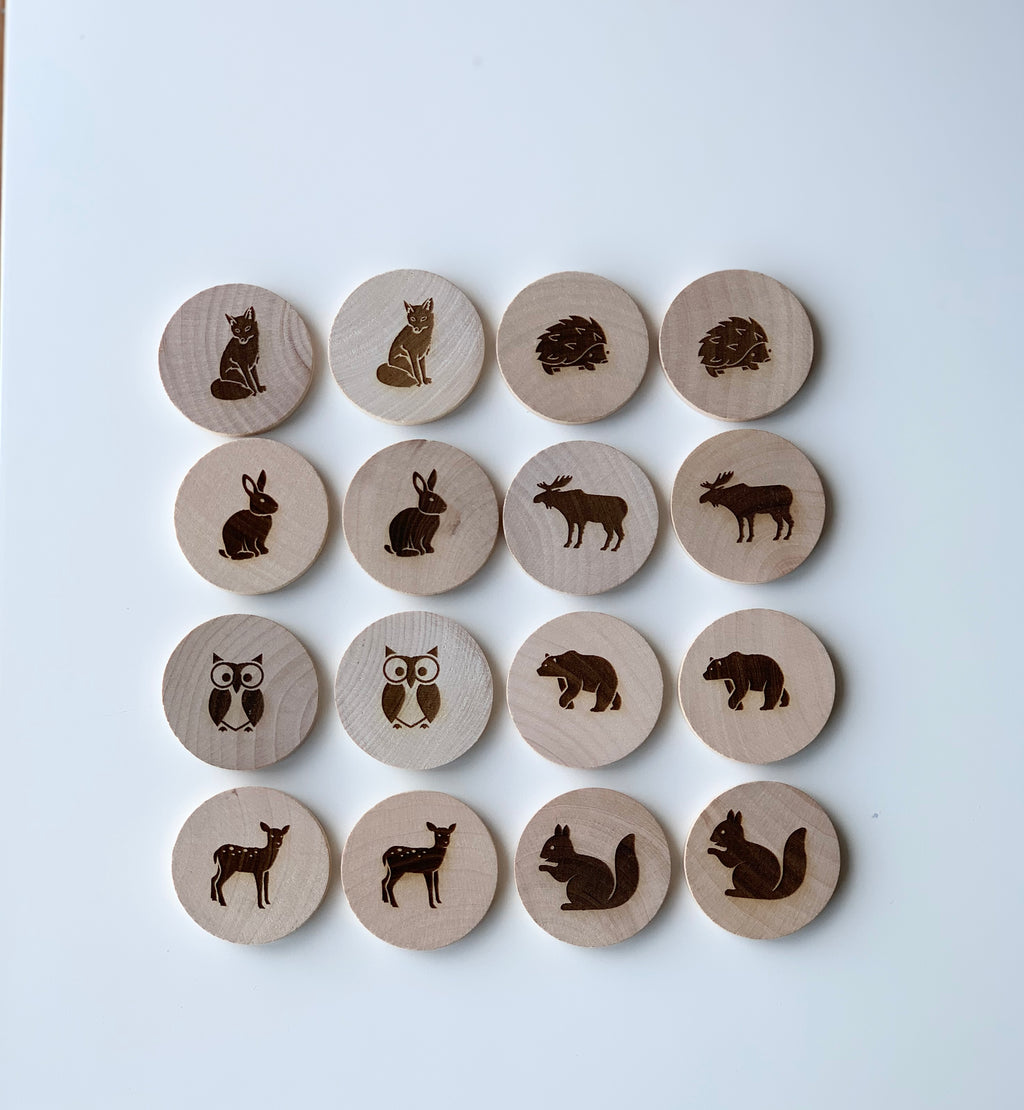 Natural wooden memory game discs with engraved woodland animal illustrations arranged in rows on white background