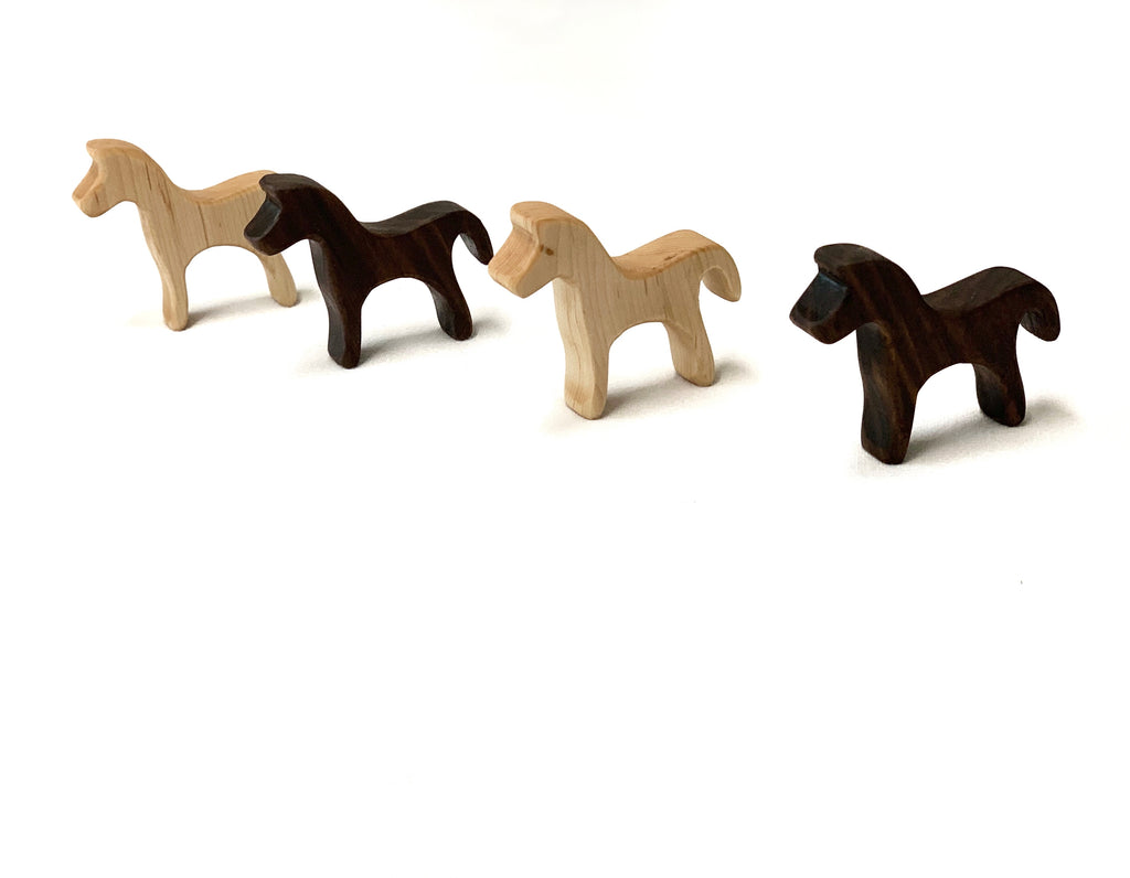 Four small wooden farm animal toy figurines in light and dark natural wood tones on white background