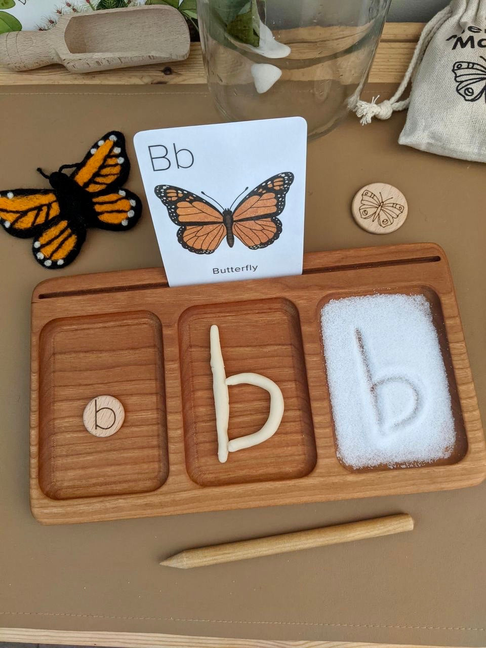 Three section wooden tray with letter b token, clay letter, and salt tracing with butterfly flash card and felt butterfly nearby