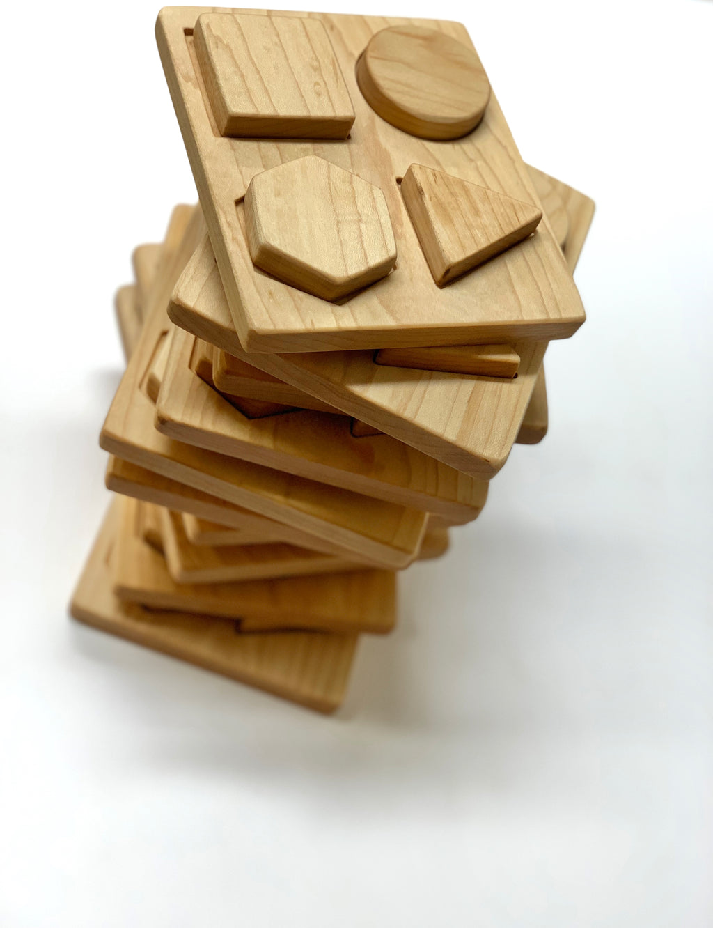 Stacked natural wooden shape puzzles with geometric pieces including circle, square, hexagon, and triangle on white background
