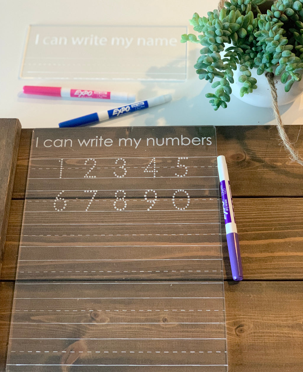 Clear acrylic dry erase board engraved with numbers 1 to 10 for tracing and learning on wooden surface with markers nearby