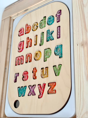 Wooden uppercase alphabet puzzle insert with colorful glitter resin letters on natural wood Flisat tabletop