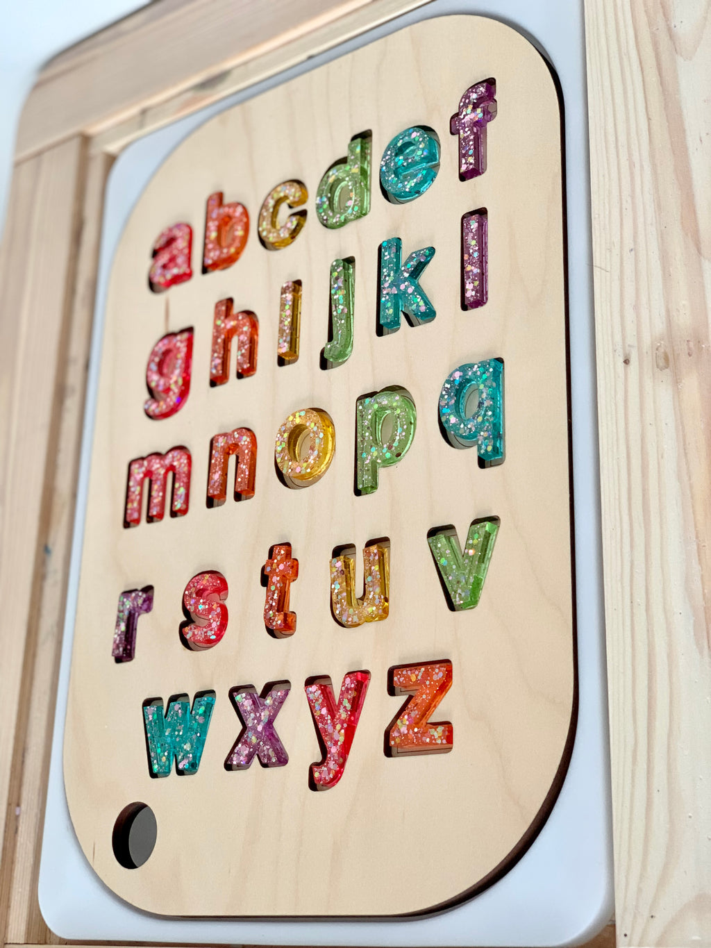 Wooden uppercase alphabet puzzle insert with colorful glitter resin letters on natural wood Flisat tabletop