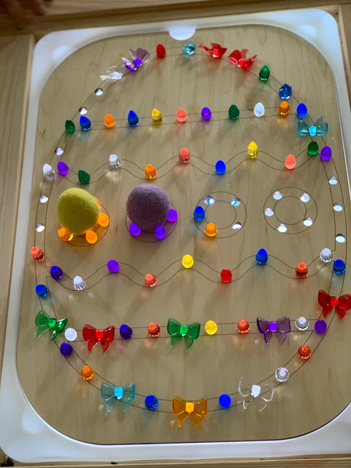Light Up Easter Egg Flisat Insert with colorful pegs, felt balls, and butterfly-shaped decorations on wooden tabletop