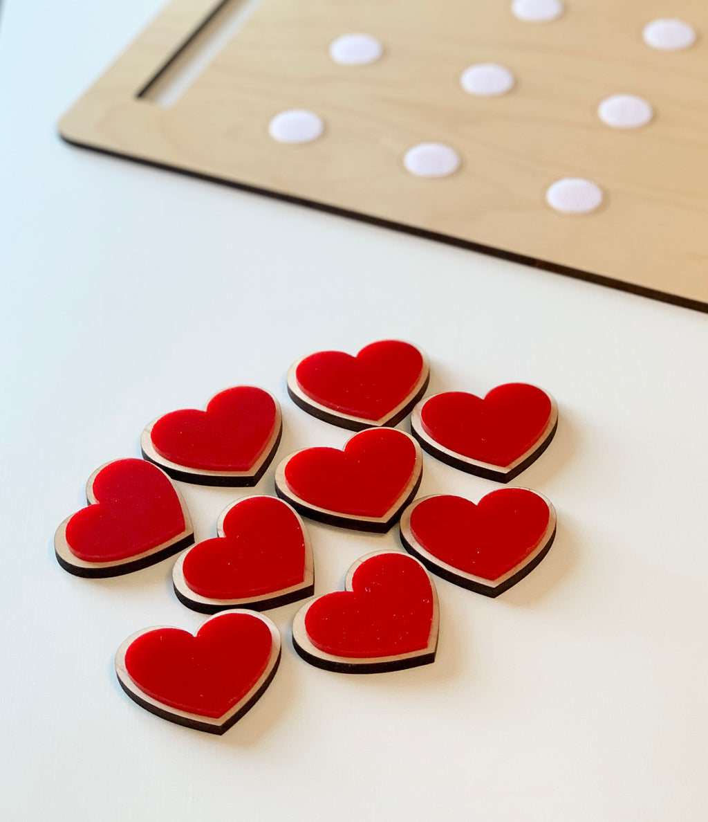 Wooden cookie sheet with white velcro dots and red heart-shaped cookies with hook and loop backing on white surface