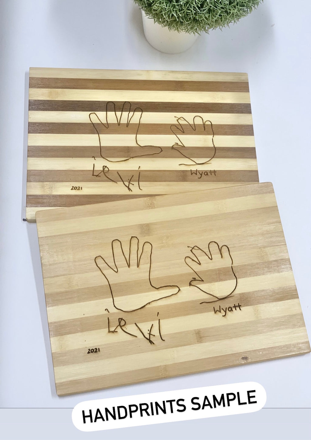 Personalized striped wooden cutting boards with engraved handprints and names on light and dark wood grain surface