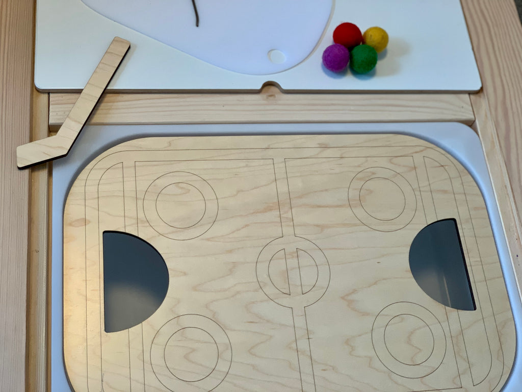 Wooden Flisat table top hockey insert with engraved rink design, wooden hockey stick, and colorful felt balls on wood surface