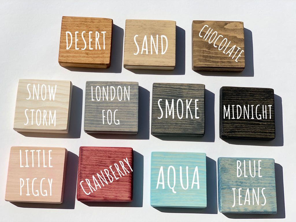Natural wooden 2-inch alphabet blocks in various stained colors with engraved white capital letters on white background
