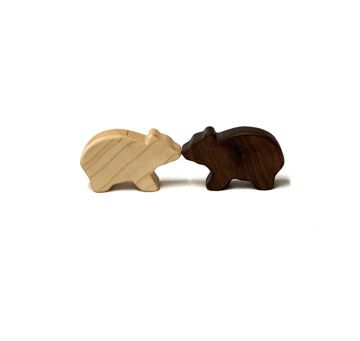 Two small wooden bear toy figurines in light and dark natural wood tones on white background