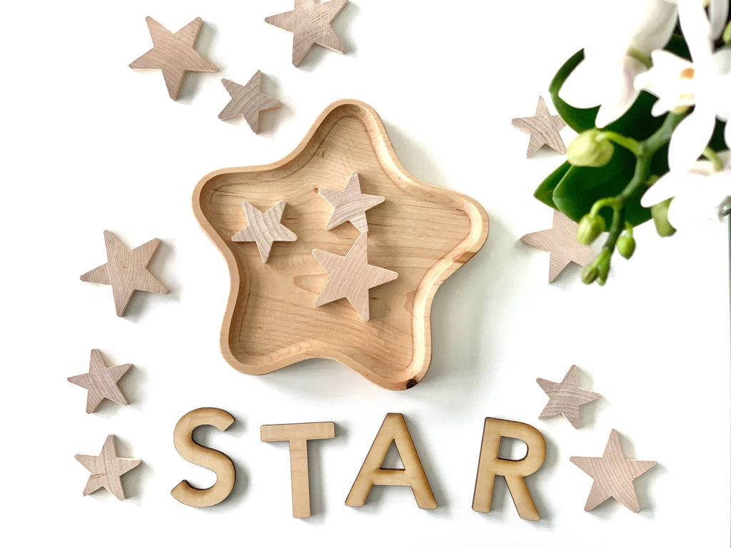 Natural wooden star-shaped sensory tray with assorted small wooden stars and wooden letters spelling STAR on white background