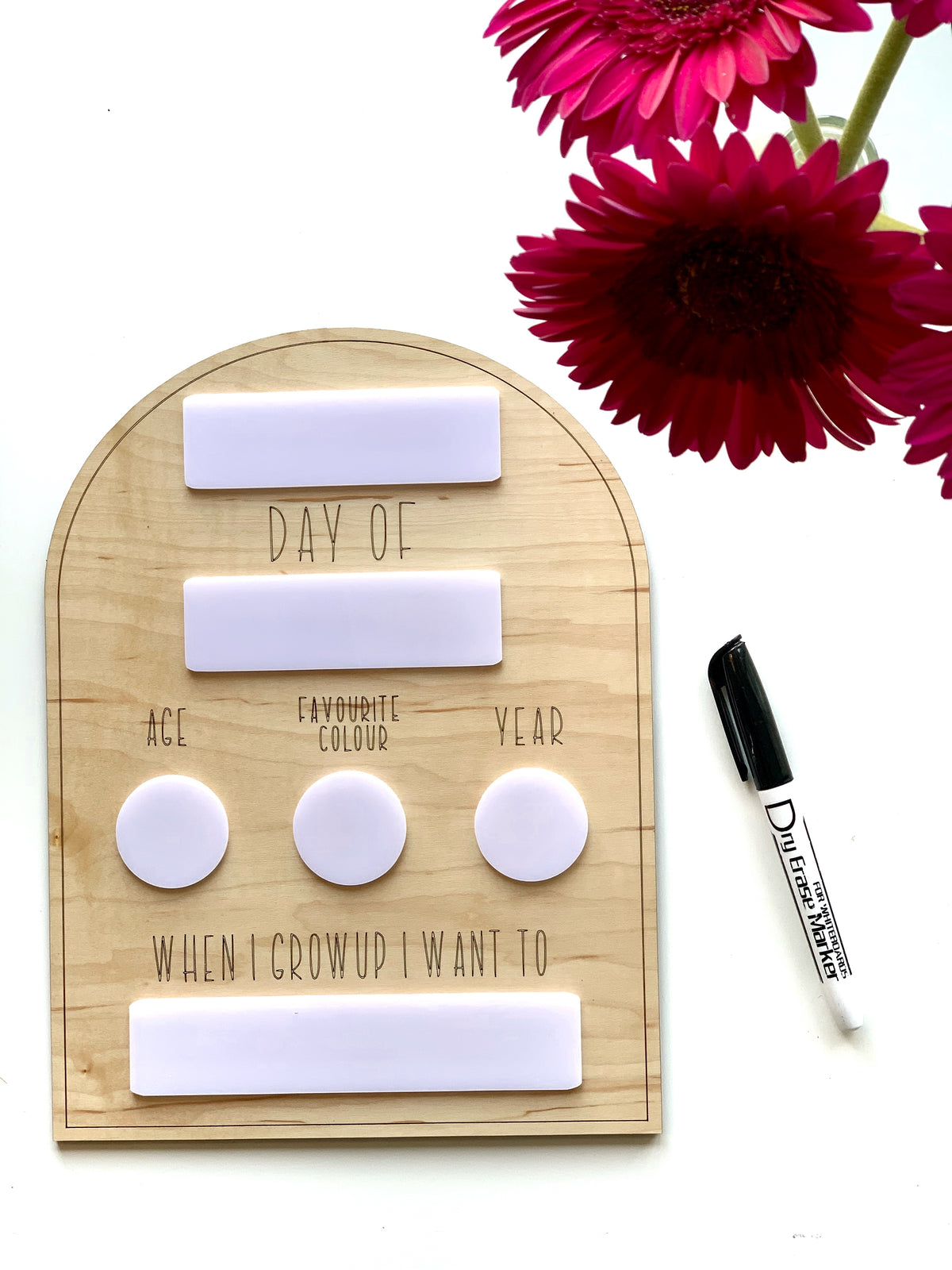 Natural wooden dry erase back to school sign with white writable sections and black marker next to pink flowers on white background
