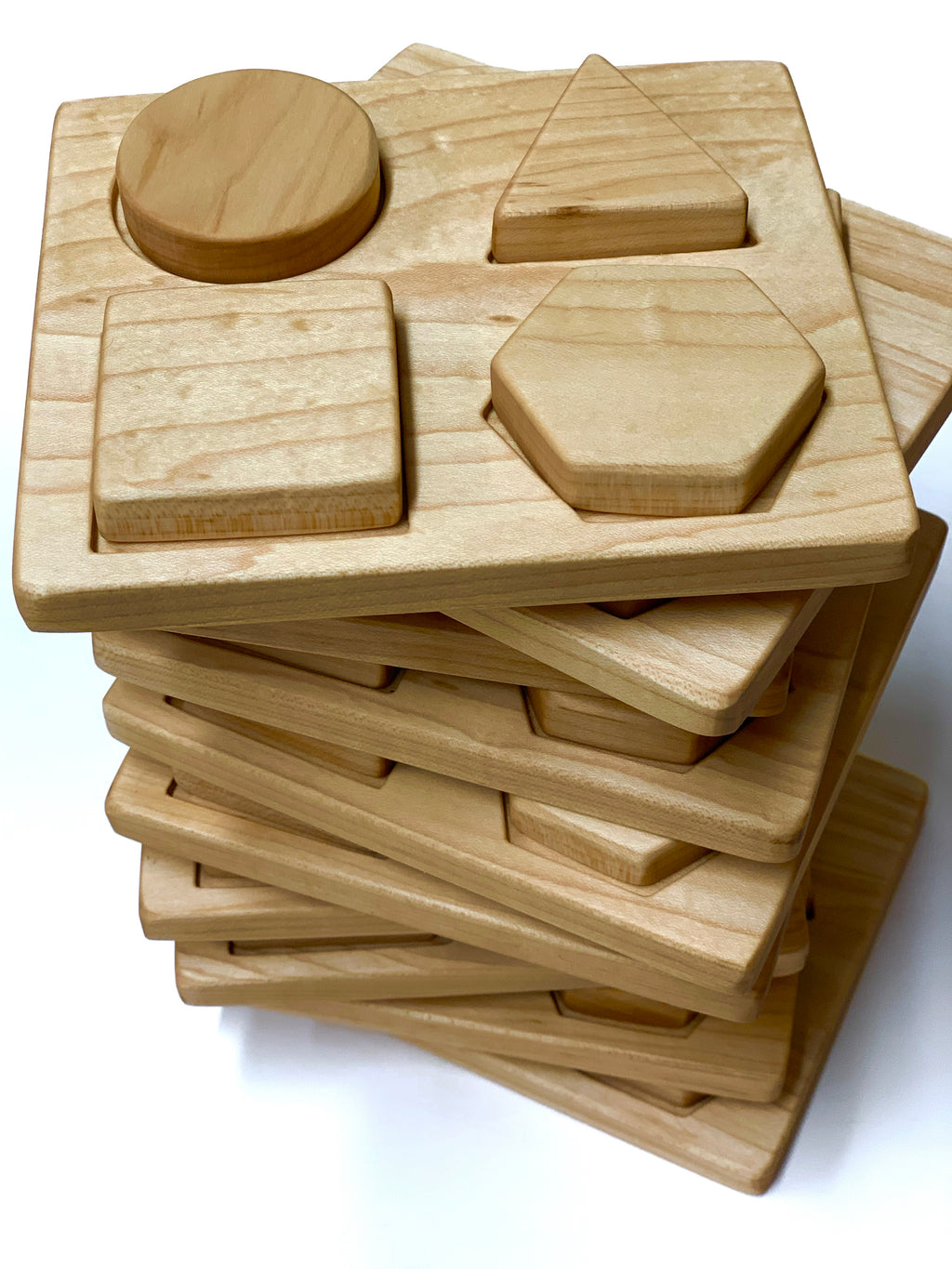 Stacked natural wooden shape puzzles with circle, triangle, square, and hexagon pieces on light background