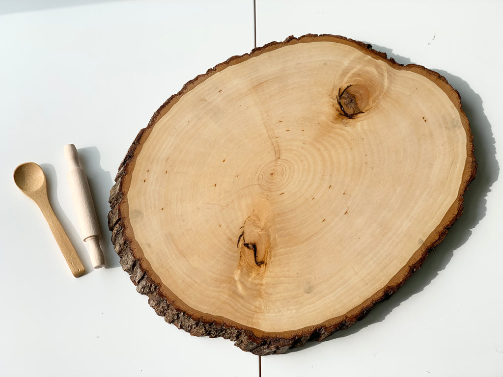 Live edge wooden tray with natural bark edges and two small wooden utensils on white surface