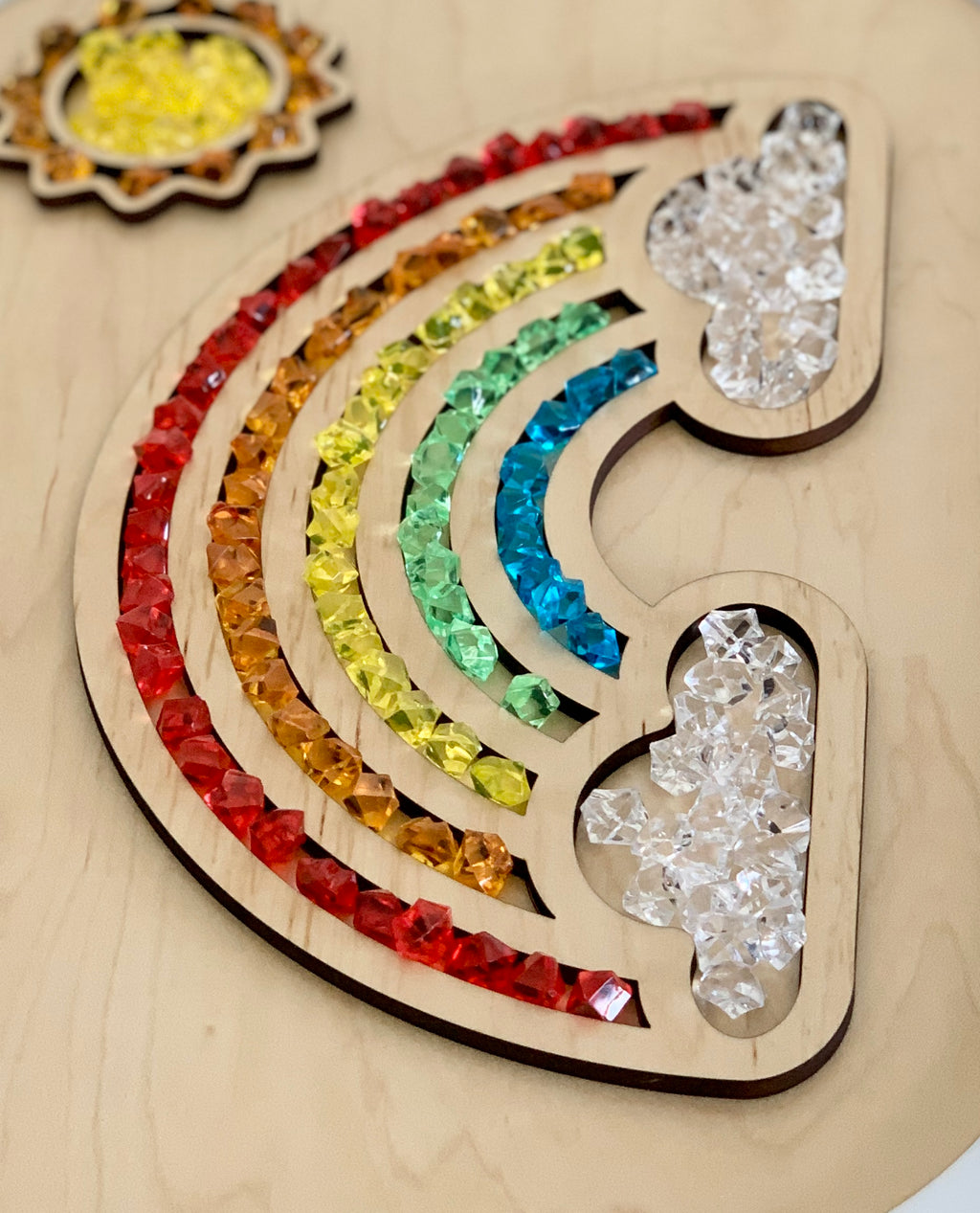 Wooden fillable rainbow table top insert with colorful acrylic gems arranged in red, orange, yellow, green, and blue arcs with cloud shapes