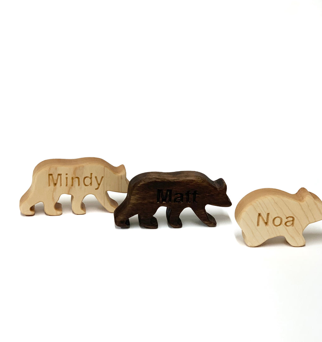 Three small custom wooden animal figurines with personalized engraved names Mindy Matt and Noa on white background