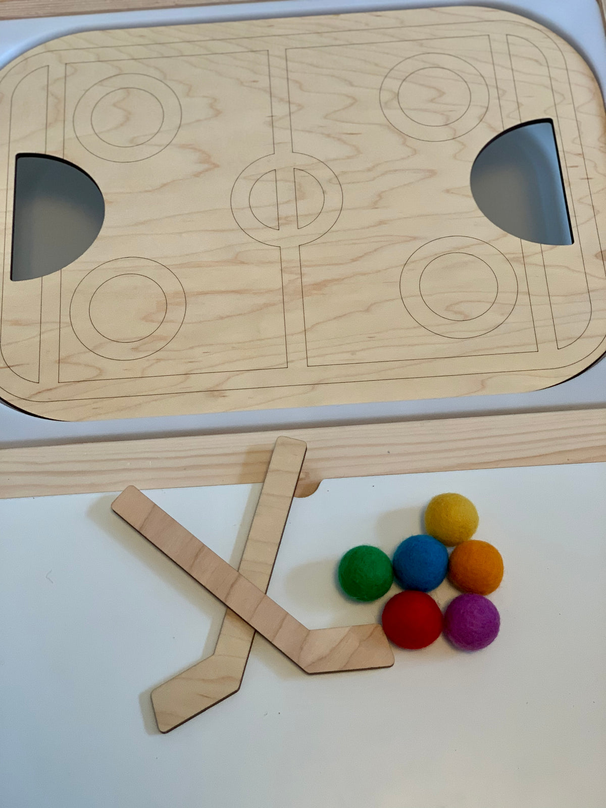 Wooden tabletop hockey insert for Flisat bin with two wooden sticks and colorful felt balls on white surface