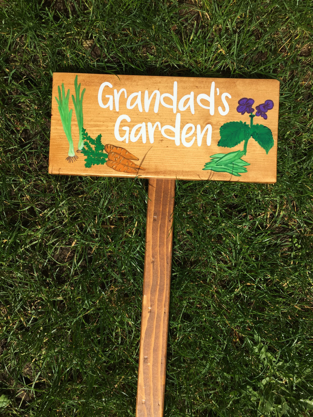 Large custom wooden garden sign with white cursive letters and painted vegetable and flower illustrations on natural wood background