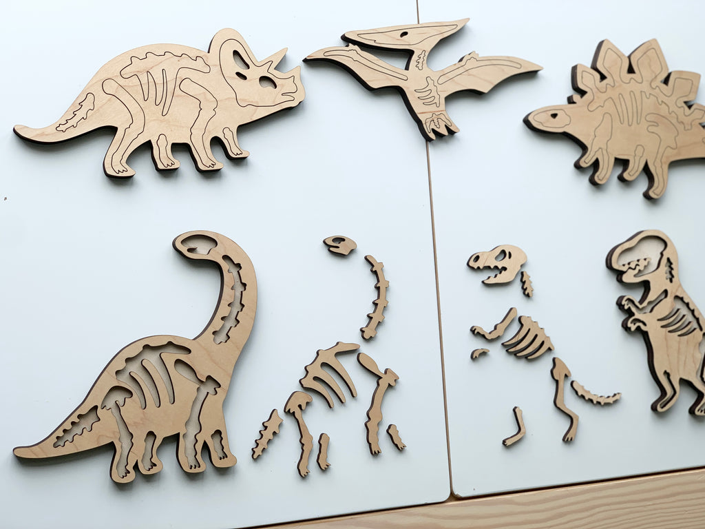Wooden dinosaur skeleton puzzle pieces including Triceratops, Pterodactyl, Stegosaurus, and T-Rex on white background