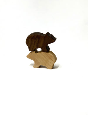 Two small handcrafted wooden bear figurines stacked on white background with natural wood grain visible
